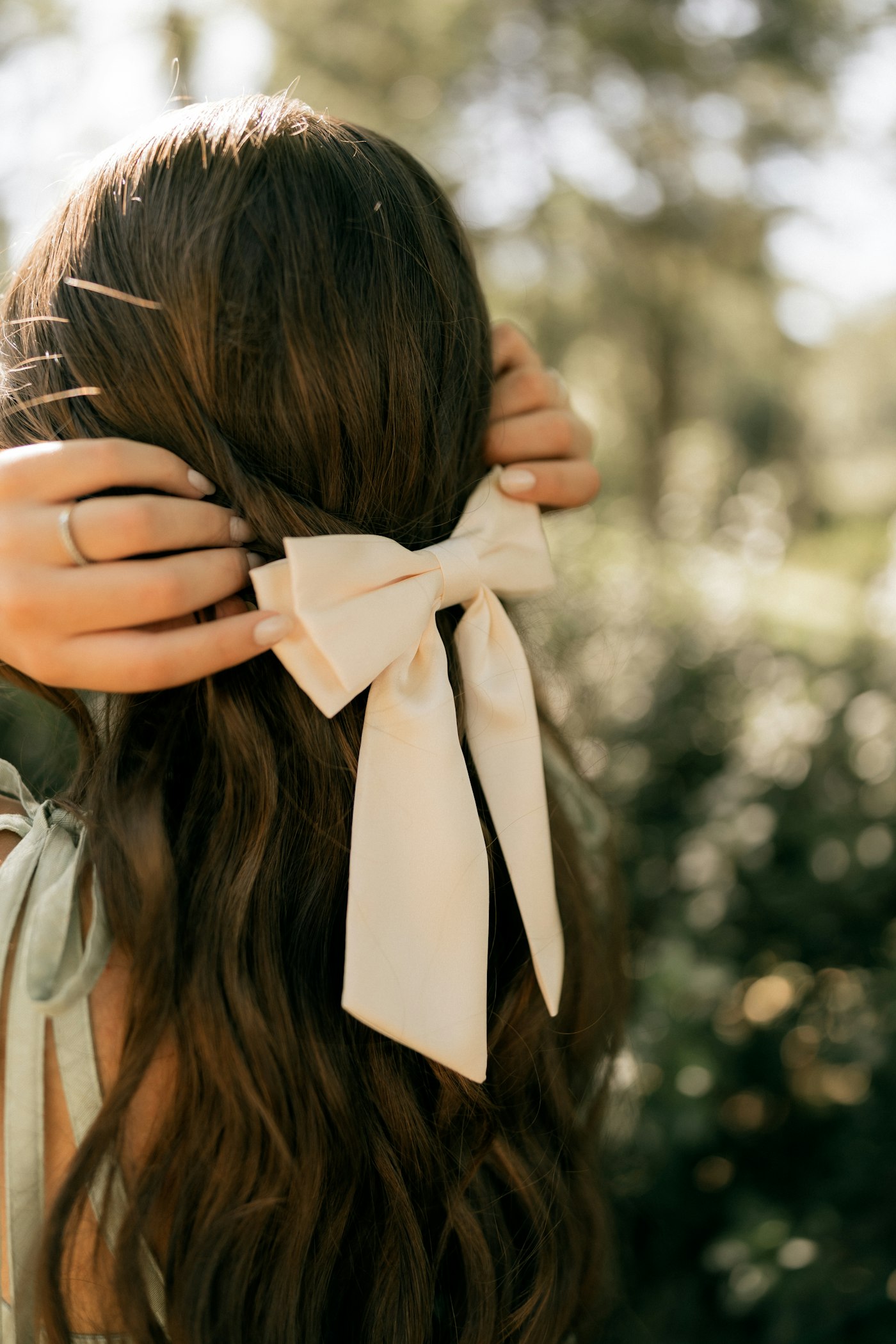 Longs cheveux bruns ondulés ornés d’un nœud crème
